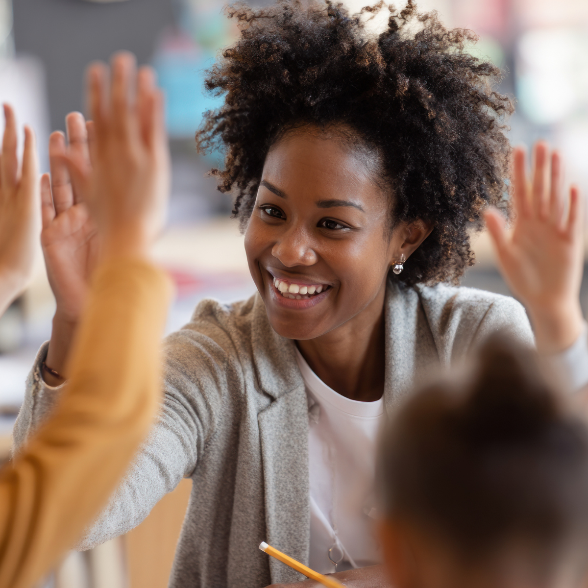 Smiling teacher high-fiving students in a classroom.