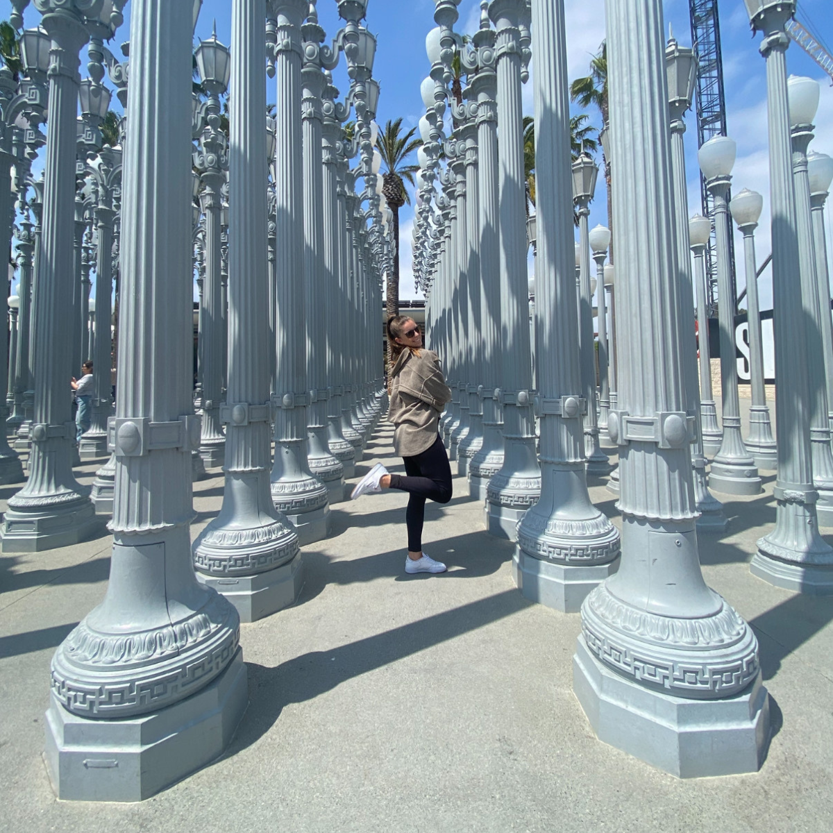 Charlotte J standing among the “Urban Light” installation at LACMA in Los Angeles during her travel OT assignment with Pioneer Healthcare
