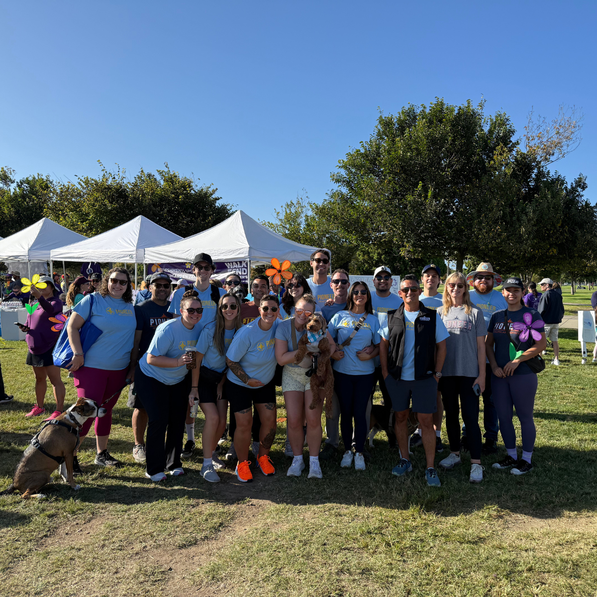 Pioneer Healthcare team in light-blue shirts at San Diego’s Walk to End Alzheimer’s, standing together with flower pinwheels.