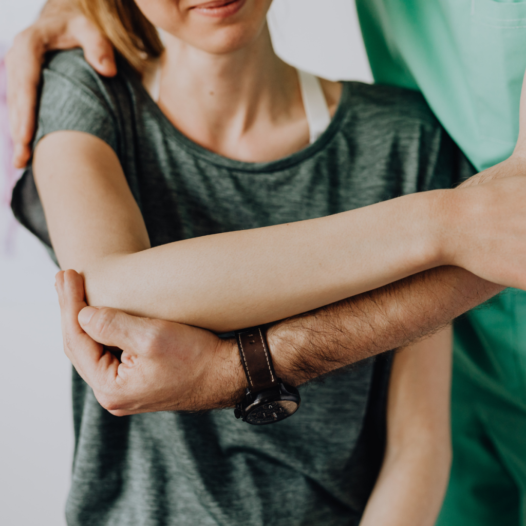 Physical therapy assistant helping a patient with arm mobility exercises during rehabilitation session. 