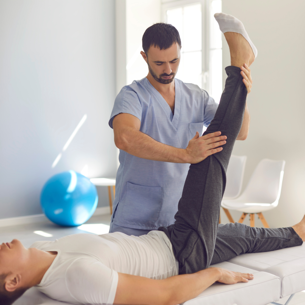 Physical therapist assisting a patient with a leg stretching exercise on a treatment table.