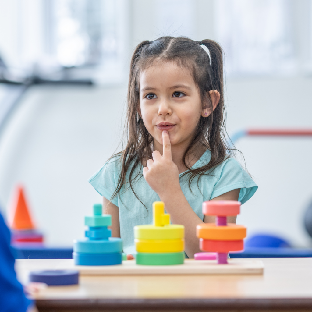 Occupational therapy assistant guiding a child through a fine motor skill exercise with colorful stacking toys. 