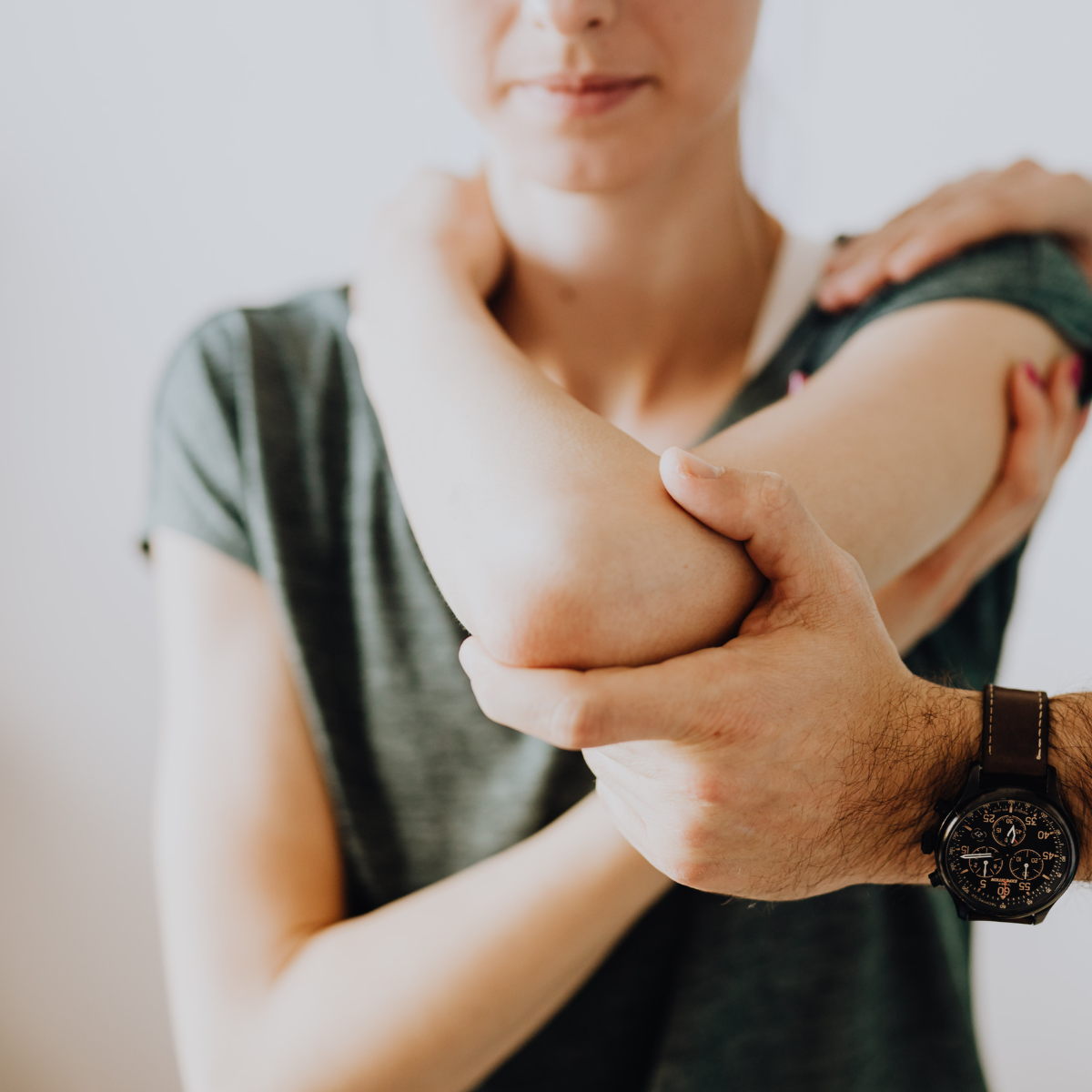 A clinician providing manual joint mobilization and travel therapy to a patient's arm and shoulder.