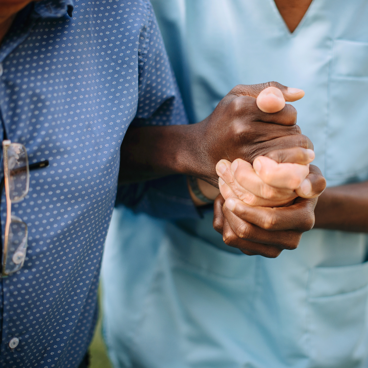 Two healthcare professionals in scrubs shaking hands in a medical setting
