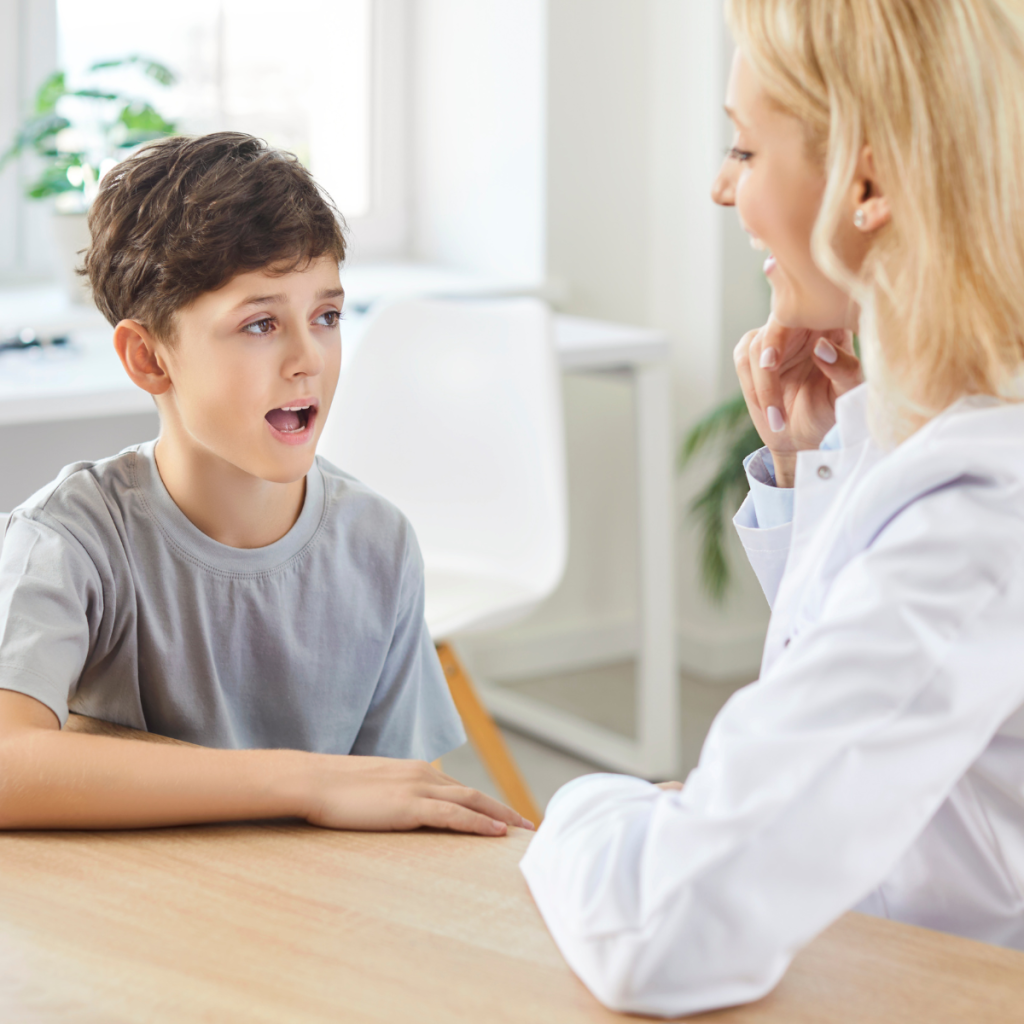 Female speech therapist sitting across from a young boy during a one-on-one speech therapy session 