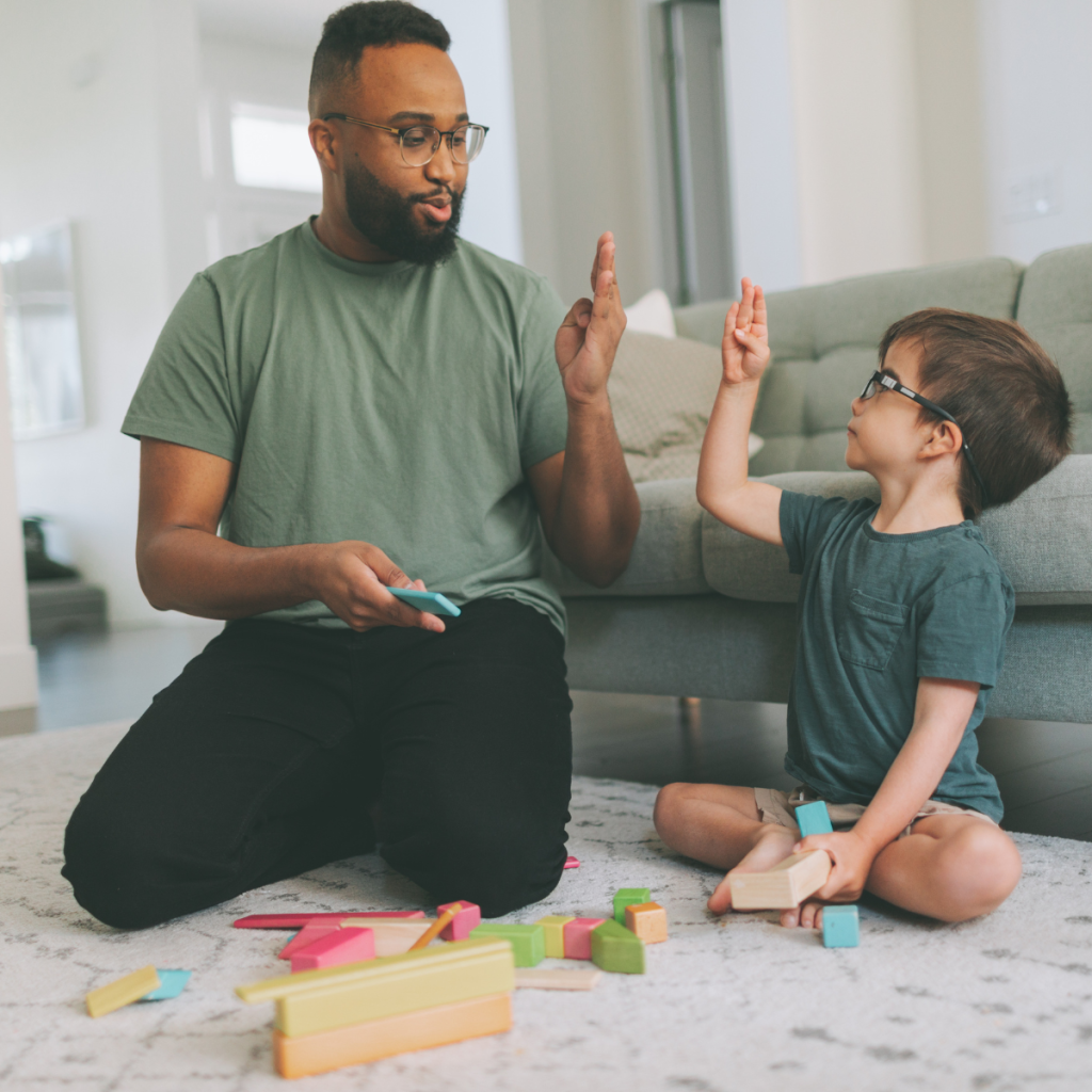 Male speech therapist using hand gestures while working with a young child on a couch during a therapy session 
