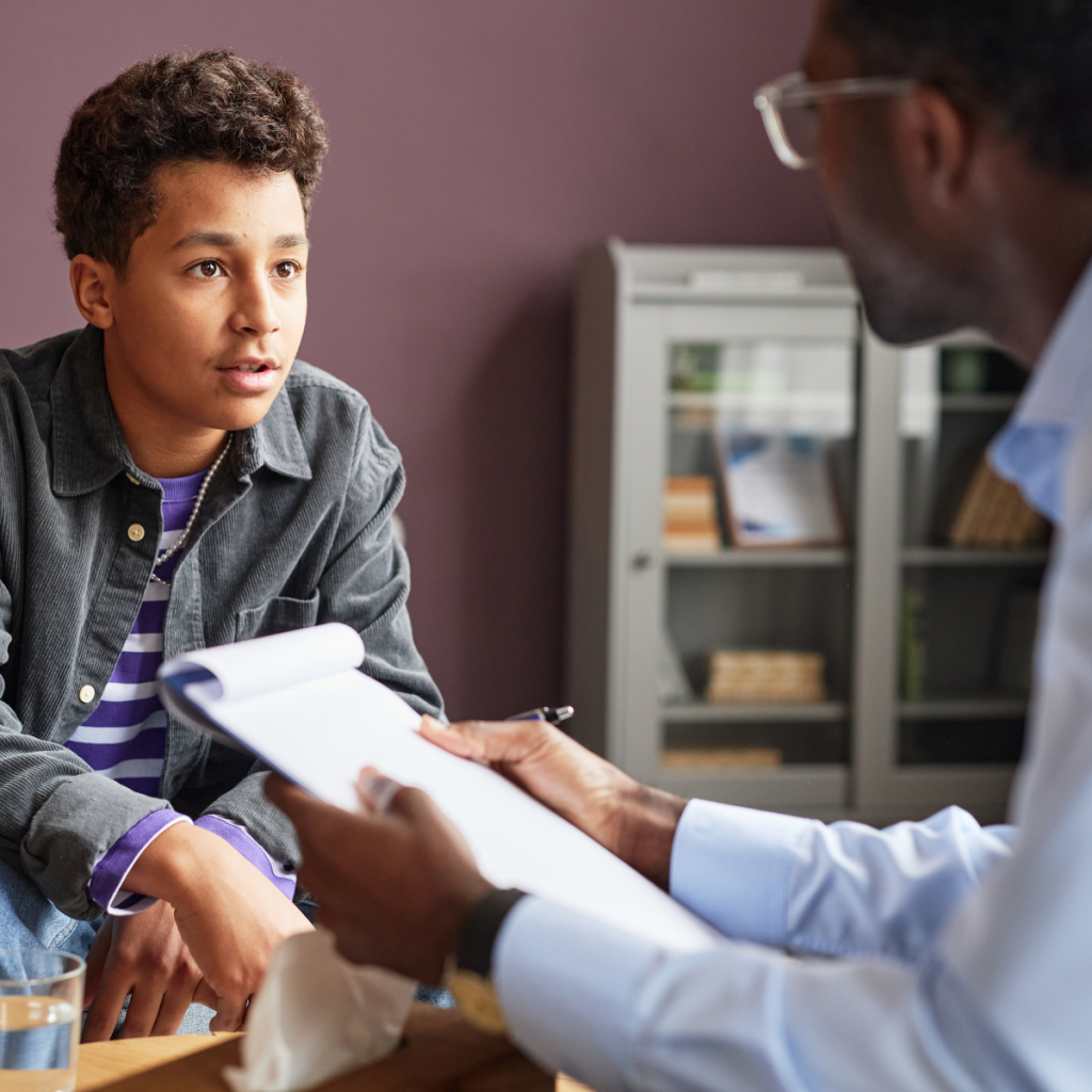 Clinical psychologist reviewing documents with teenage patient during a one-on-one psychological assessment session