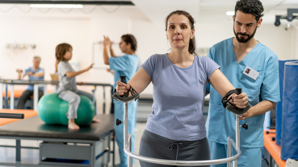 Male therapist walking behind female patient using a mobility walker during physical therapy.