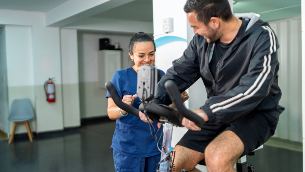 Patient doing cycling on a stationary bike with a female physical therapist providing guidance and support in a rehabilitation center