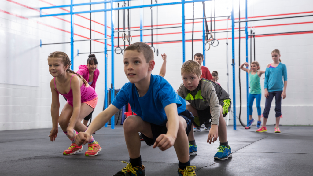 Kids doing squats in physical education class in gym