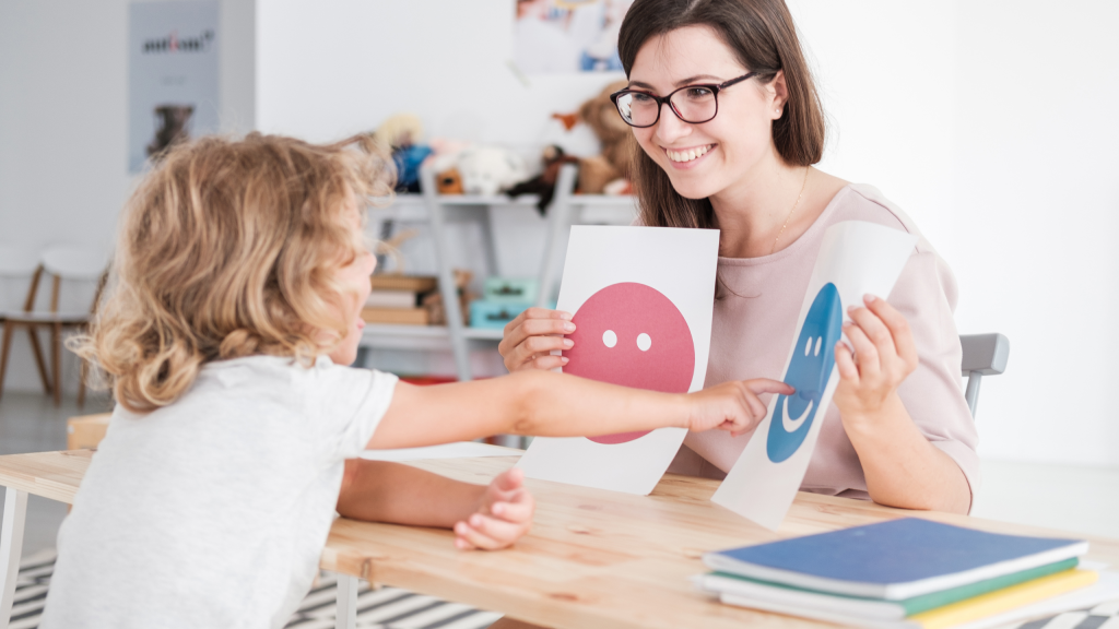 Speech language pathologist using visual cue cards to help child identify sounds during pediatric speech therapy session