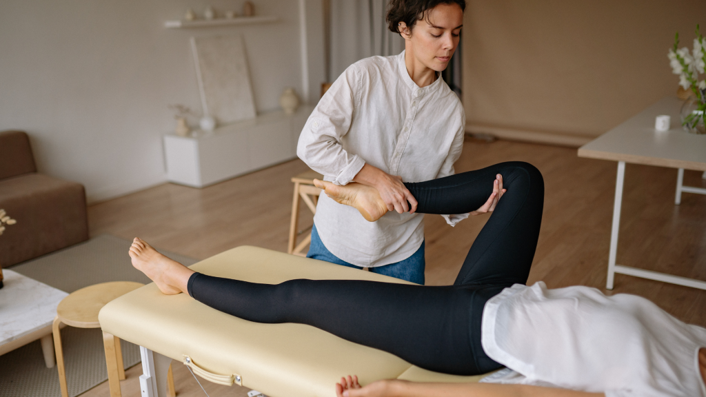PE Teacher Ideas for Fitness Activities – Squat Exercises in Physical Education Class A female therapist performing a passive leg stretch on a patient resting on a treatment table.