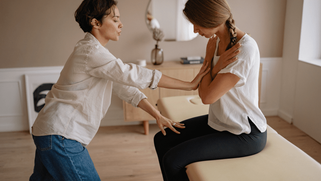 PE Teacher Ideas for Fitness Activities – Squat Exercises in Physical Education Class A female physical therapist evaluating a patient's upper back alignment and posture on an examination table.